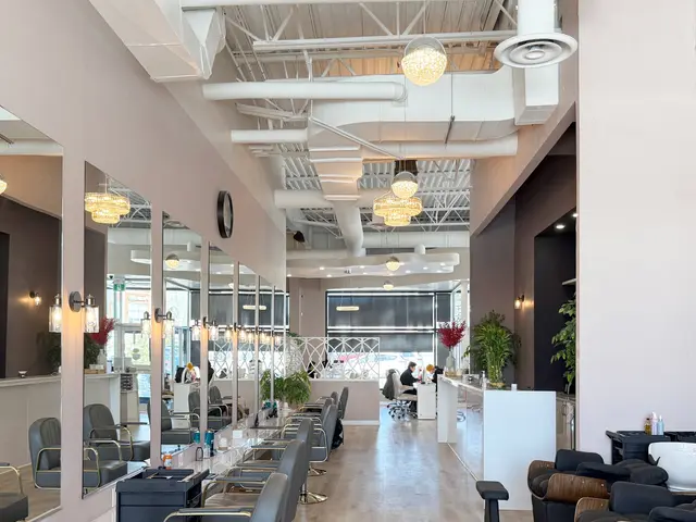Long salon interior with styling stations, pendant lights and an exposed white ceiling
