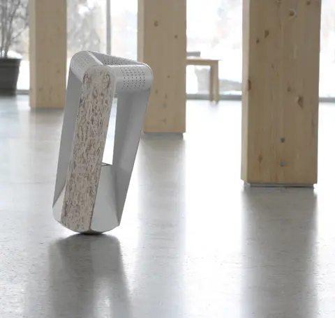 A folded white paper seat with a dark base standing on a concrete floor