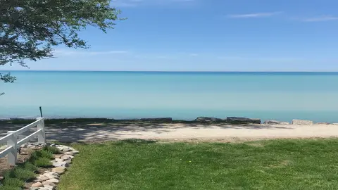 The site's view across a lawn to the turquoise water of Lake Huron