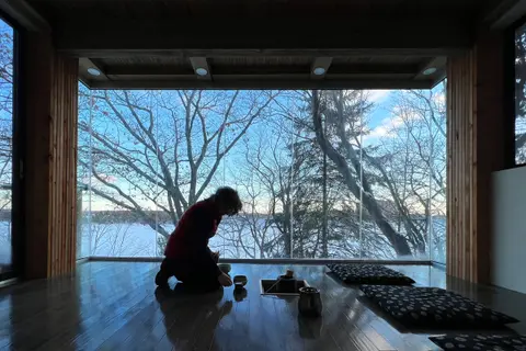 A person kneeling at a low table in the solarium in winter, silhouetted against the frozen lake