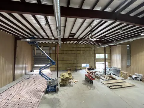 Interior during renovation, with an exposed steel deck ceiling and a lift on the new floor