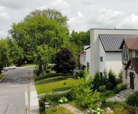 The finished house seen along the street among mature trees