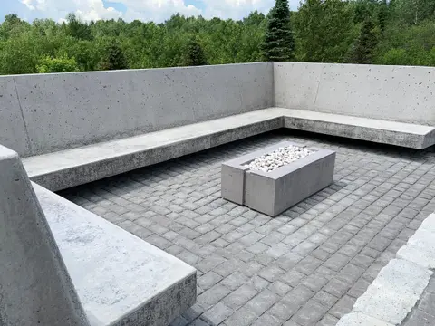Cast concrete bench wrapping a fire table on a stone patio