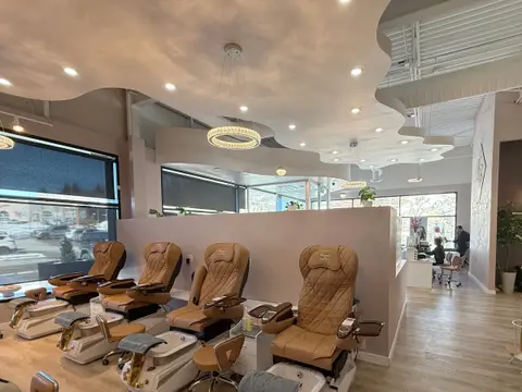 Row of pedicure chairs beneath a curved, lit ceiling bulkhead