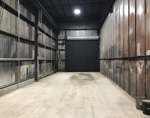 Long interior bay after renovation, with a new black overhead door at the far end