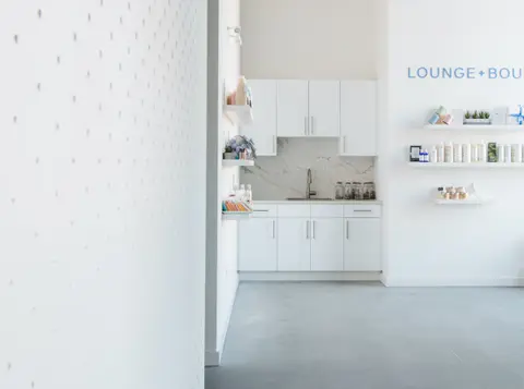 Bright lounge with white shelving and the edge of the perforated screen