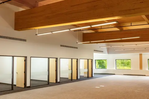 Bright second-floor office space with timber beams and glazed offices along one wall
