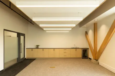 Long meeting room with a kitchenette and a diagonal glulam brace in the corner